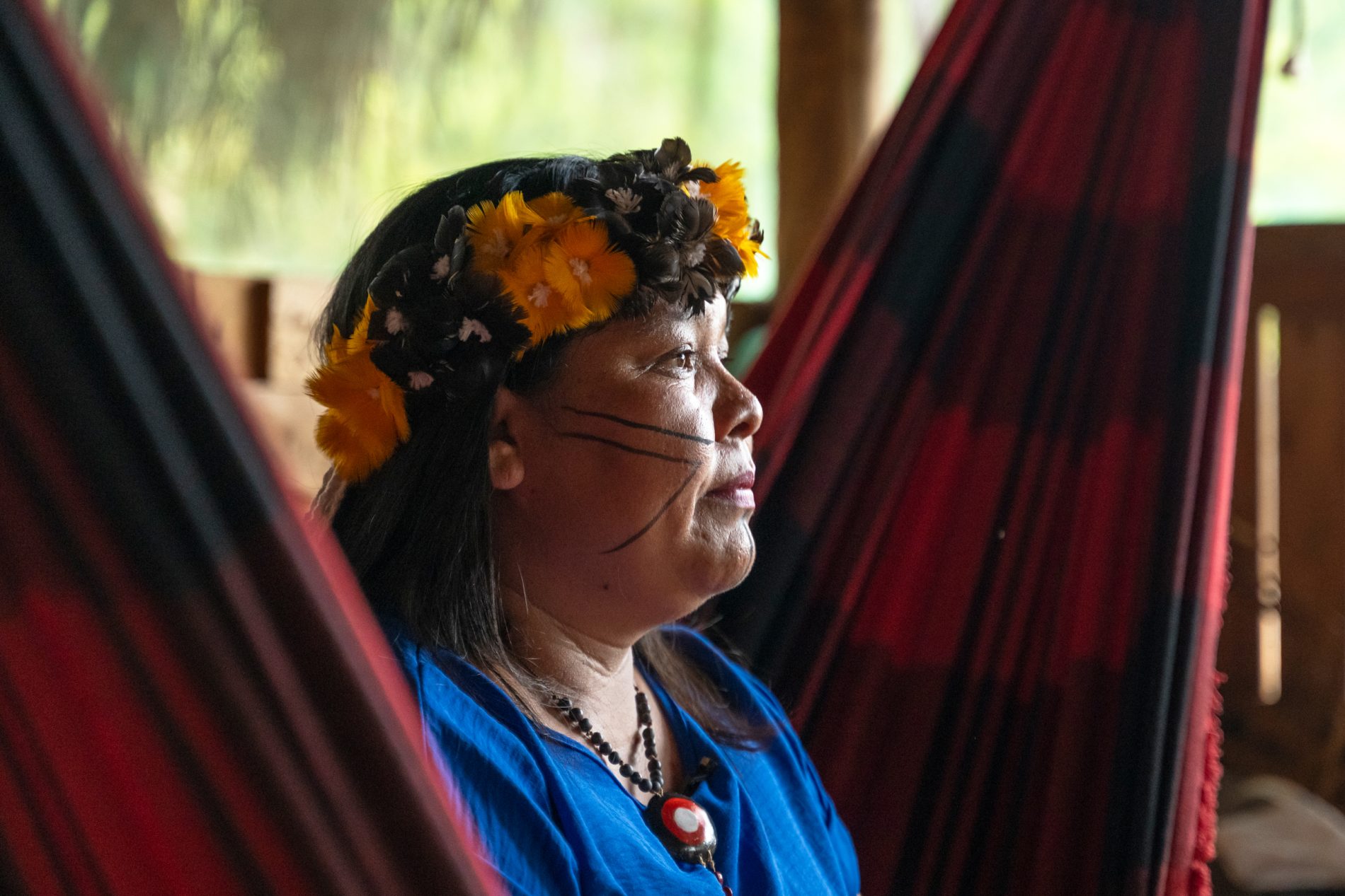 Perfil de Cleide mulher indígena, sentada em rede, olhando o horizonte.