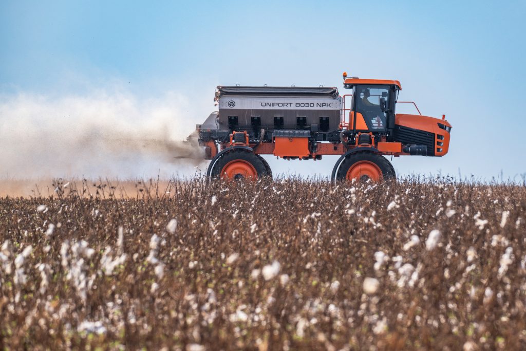 Máquina laranja solta agrotóxico, que se parece com um janto jato de fumaça, em lavoura de algodão