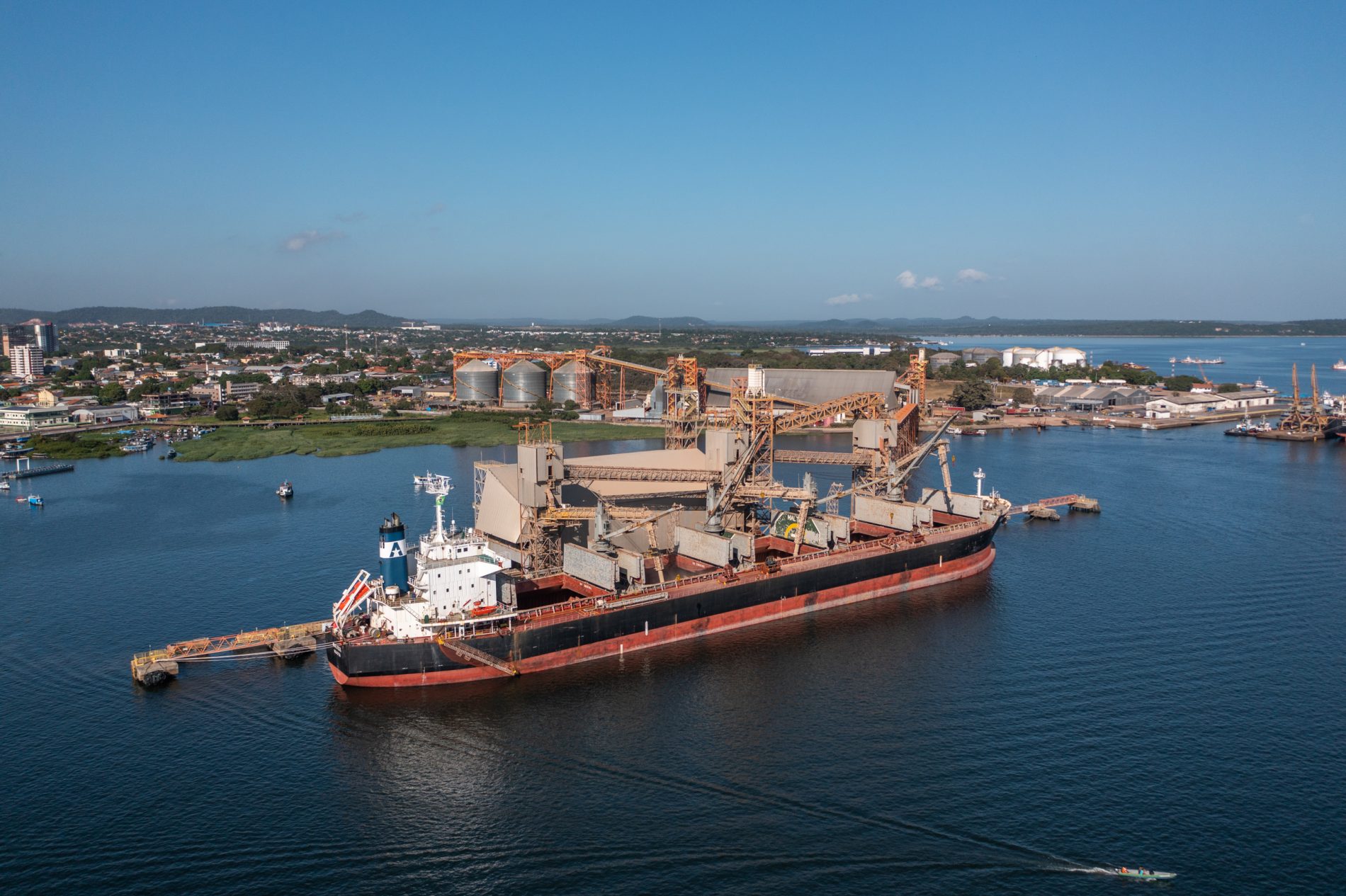 Vista aérea de navio cargueiro nas cores vermelha, branca e preta.